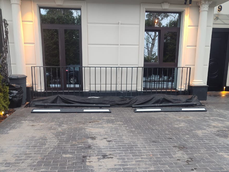 Колесоотбойники с белыми светоотражателями на парковке возле коттеджа