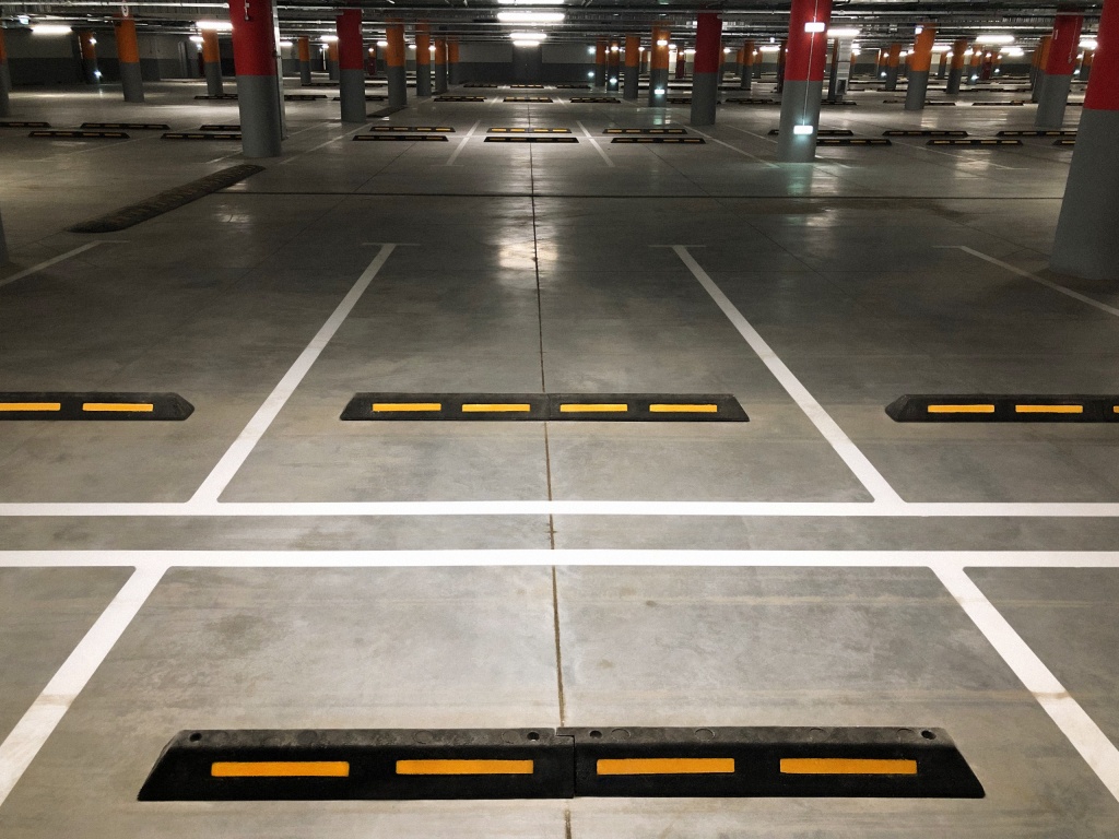 Колесоотбойники и напольная разметка для распределения парковочных мест на подземной парковке парка Колесоотбойники и напольная разметка для распределения парковочных мест на подземной парковке парка